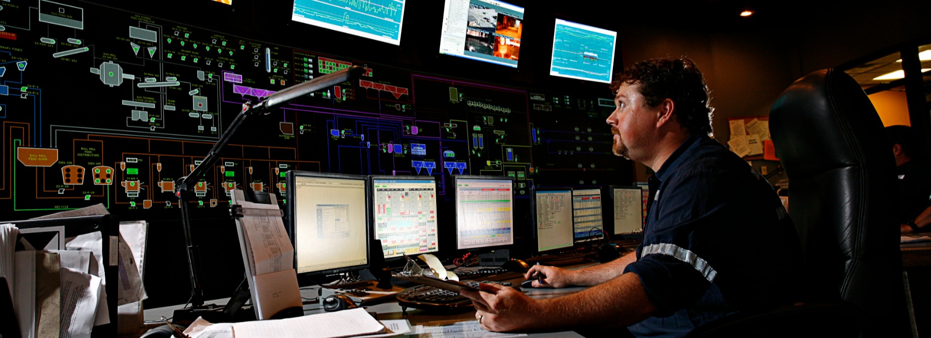 male mine operator looking at row of screens